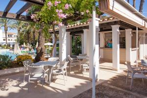 a patio with tables and chairs next to a pool at Grupotel Club Menorca in Son Xoriguer