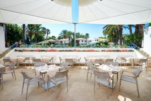 a restaurant with white tables and chairs and an umbrella at Grupotel Club Menorca in Son Xoriguer