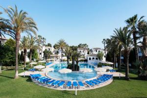 a pool with blue chairs and umbrellas and palm trees at Grupotel Club Menorca in Son Xoriguer