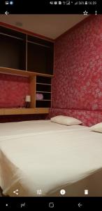 a bedroom with a large white bed with a red wall at Passion in Magong
