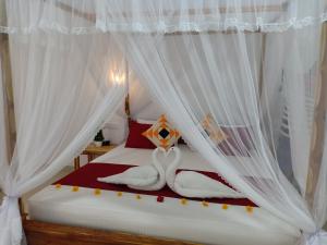 a bedroom with a bed with white curtains and two towels at Victory Villa Sigiriya in Sigiriya