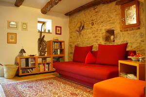 a living room with a red couch and a stone wall at Quercy Stone Gite Marcilhac in Marcilhac-sur-Célé