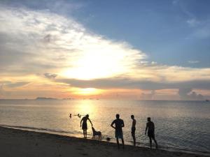 a group of people standing on a beach with a dog at Jasmine & Tea House in Mae Nam