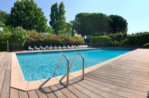 una piscina con sillas junto a una terraza de madera en Bungalows & Rooms - Gît'Ôstal, en Carcassonne