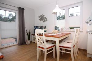 een eetkamer met een tafel, stoelen en ramen bij Haffmuschel in Zirchow