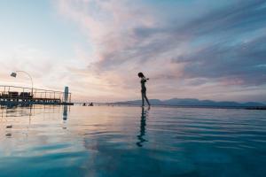 a woman standing on a body of water at Emelisse Nature Resort in Fiskardho