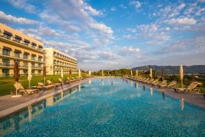 a large swimming pool with chairs and a building at Vila Gale Collection Sintra in Sintra