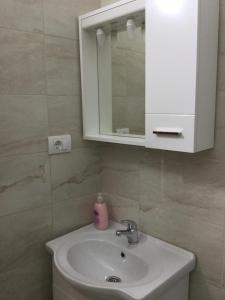 a bathroom sink with a cabinet and a pink soap dispenser at Apartments Ismy in Ulcinj +40 photos