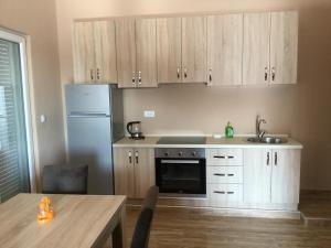 a kitchen with wooden cabinets and a table and a refrigerator at Apartments Ismy in Ulcinj