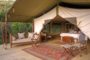 Zelt mit einem Bett, einem Sofa und Stühlen in der Unterkunft Entumoto Main Camp in Ololaimutiek