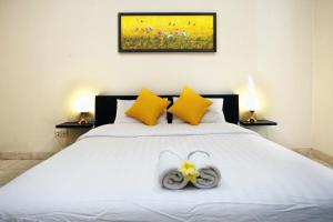 a bedroom with a white bed with yellow pillows at Cameng Homestay in Denpasar