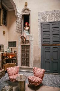 ein Zimmer mit zwei Stühlen und einer Puppe am Fenster in der Unterkunft Riad Anata in Fès