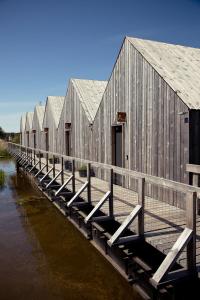 a row of wooden buildings next to a body of water at Peldmaja in Pāvilosta