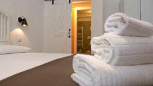 een stapel handdoeken bovenop een bed bij Cardìlle Apartment in Monopoli +18 foto's