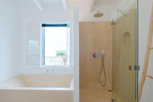 a bathroom with a tub and a shower with a window at LLONGA'S 11th in Ciutadella