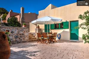 a patio with a table and chairs and an umbrella at Metochi Villas in Spílion