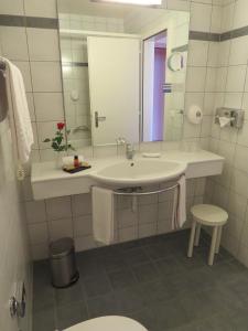 a white bathroom with a sink and a mirror at Hôtel du Port in Lausanne