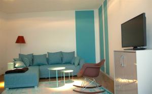 a living room with a blue couch and a tv at Exklusive 2-Zimmer-Wohnung am Schloss Bensberg in Bergisch Gladbach