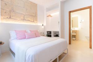 ein Schlafzimmer mit einem großen weißen Bett mit rosa Kissen in der Unterkunft LLONGA'S 11th youth Hostel in Ciutadella