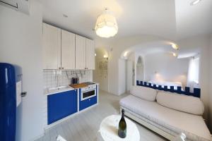 a living room with a white couch and a blue and white kitchen at Central Apartments Integrated Hotel in Zadar