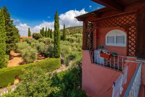 a house with a balcony overlooking a garden at Casale Gli Ulivi in Orbetello