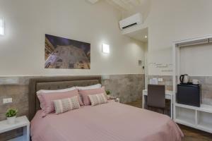 ローマにあるNavona Charme Suiteのピンクベッド1台とテレビ付きのベッドルーム1室