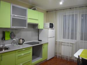 ヴォログダにあるАпартаменты на Ярославской 33のキッチン(緑のキャビネット、白い冷蔵庫付)