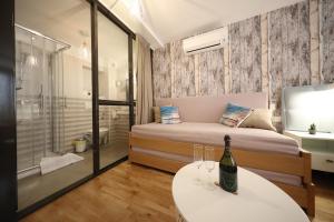 Un dormitorio con una cama y una mesa con una botella de vino en Central Apartments Integrated Hotel en Zadar