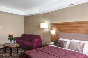 ブリャンスクにあるGrand Hotel Bezhitsaのベッドと赤いソファが備わるホテルルームです。