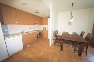 a kitchen with a wooden table and chairs and a kitchen with a sink at Bouganvilla in L'Ampolla