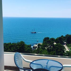 a table and chair on a balcony with a boat in the ocean at IdealHouse Apartments in Ulcinj