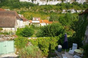 einen Garten mit einem Sonnenschirm, einem Tisch und Stühlen in der Unterkunft Quercy Stone Gite Marcilhac in Marcilhac-sur-Célé