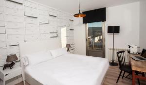 Habitación blanca con cama blanca y escritorio. en La Casita de la Planta en Quintanilla de Onésimo