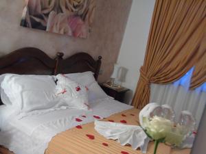 1 dormitorio con 1 cama con almohadas blancas y rosas en Agriturismo Cascina Lavaroni en Buttrio