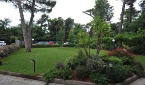 a park with a green lawn with plants and trees at Hotel Riviera Blu in Tirrenia