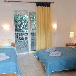 a hotel room with two beds and a balcony at Hotel Nestor in Toroni