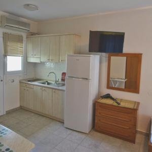 a kitchen with a white refrigerator and a sink at Hotel Nestor in Toroni
