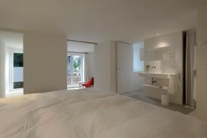 a white bedroom with a large bed and a desk at BAR10ZIMMER in Dornbirn