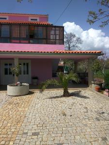 una casa rosa con una palmera delante de ella en Joaquim do Norte, en Podence