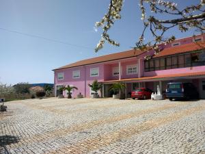 un edificio rosa con coches estacionados frente a él en Joaquim do Norte, en Podence