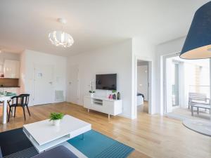 ein weißes Wohnzimmer mit einem weißen Tisch und einer Küche in der Unterkunft VacationClub - Przy Plaży Apartment 23 in Mielno