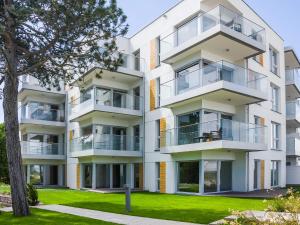 an apartment building with balconies and a tree at VacationClub - Przy Plaży Apartment 23 in Mielno