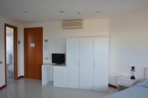 a bedroom with a white closet and a tv at Hotel Sirenetta in Grado