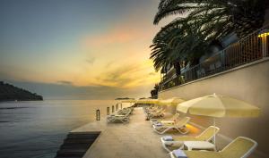 - une rangée de chaises longues et de parasols sur la plage dans l'établissement Aminess Lume Hotel, à Brna