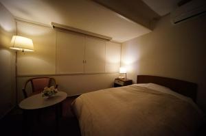 a bedroom with a bed and a table and a lamp at 館林グランドホテル in Tatebayashi
