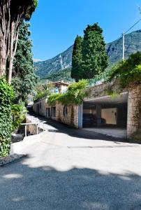 a stone building with a garage and trees and mountains at Beach Hotel Du Lac Malcesine in Malcesine