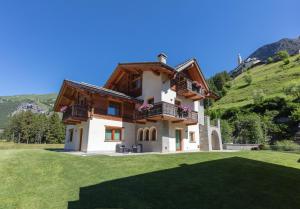 ein Haus auf einem Hügel mit einem grünen Hof in der Unterkunft Chalet Roberta in Valdidentro