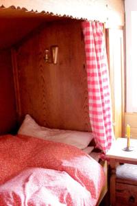 a bed with a wooden headboard with a red and white curtain at Haus Poxleitner in Mauth