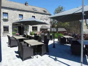 a patio with tables and umbrellas in front of a building at Hotel le Fenil in Celles