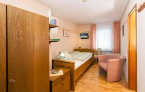 a small bedroom with a bed and a chair at Pension und Weingut Moselblick in Brauneberg